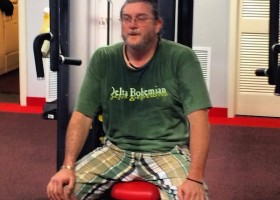 Man in green shirt sitting on weight machine.