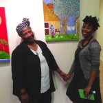 Two women stand in front of artwork.