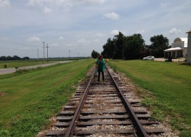 Woman walking on train tracks in rural setting.