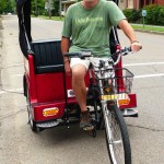 Man riding a red tricycle with a basket.