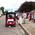 Bride and groom in a red decorated car.