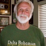 Smiling man wearing a green "Delta Bohemian" shirt.