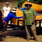 Three people loading a canoe on a trailer.