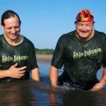 Two men in a river wearing "Delta Bohemian" shirts.