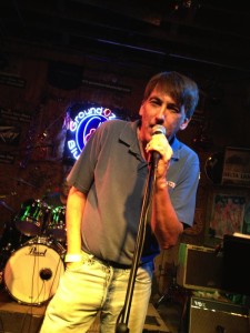 Man singing into microphone on stage.
