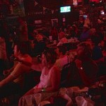 Group of people at a bar, dimly lit.