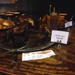 BBQ ribs on a platter with tongs and a sign.