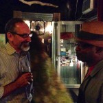 Two men, one holding a glass of wine.