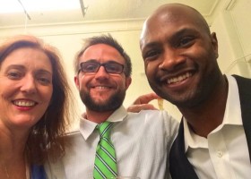 Three people smiling, one with a green tie.