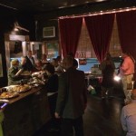 People gathered in a dimly lit room with desserts.