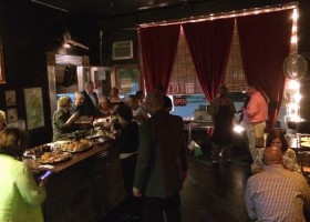 People gathered in a dimly lit room with desserts.