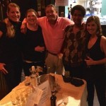 Four friends smiling together at a bar.