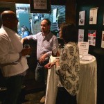 Three people standing in a bar with drinks.