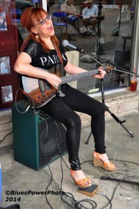 Woman playing electric guitar on stage.