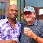 Two men in plaid shirts, smiling and holding drinks.