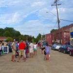 People gather outside a storefront in a town.