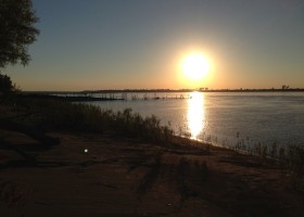 Sunset over a river with a bright sun.