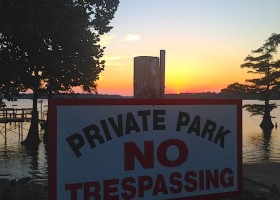 Private park sign at sunset, no trespassing.