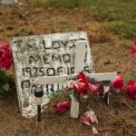 Gravestone with a white cross and flowers.