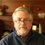 Man with glasses and beard in blue sweater.