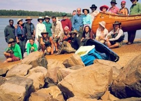 Group of people by a canoe on rocks.