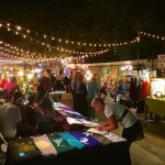 Night market with string lights and art.