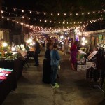 Night market with string lights and shoppers.