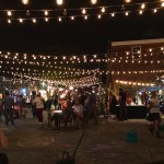 Night market with string lights and people.