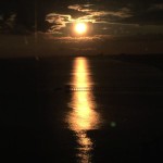 Sunset over water with a pier.