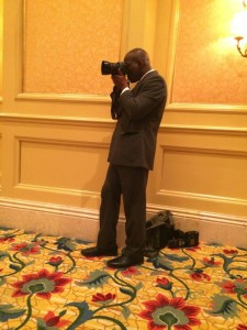 Man in suit taking a photo with camera.