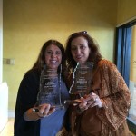 Two women holding awards for magazine and resort.