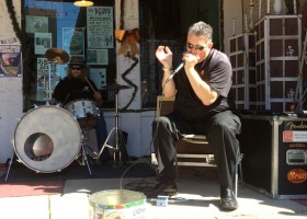 A man singing into a microphone with a drummer behind him.