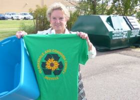 Woman holding a green recycle t-shirt.