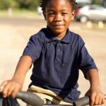 Smiling boy riding a bike outdoors.