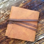 Brown leather journal on weathered wood.