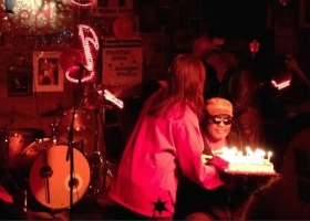 Woman in red lighting a birthday cake.