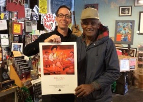 Two men holding a poster in a store.