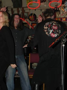 Three people singing karaoke at a bar.