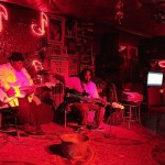 Two musicians playing guitars in a dimly lit room.