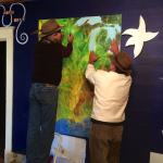 Two men pointing at a map on a wall.