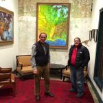 Two men standing in a room with artwork.