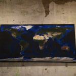 Framed map of the world on a wall.