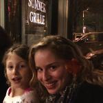 Two girls smiling in front of a restaurant.