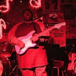 Man playing electric guitar on stage.