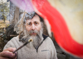 Man with long beard holds a stick.