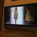 Two women wearing dresses on a TV screen.