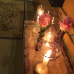 Candles and pink roses in sand.