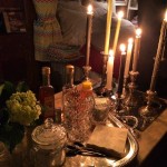 Candlelight table setting with bottles and flowers.