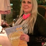 Woman holding a glass of wine and a magazine.