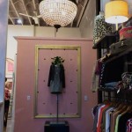 Pink room with a chandelier and clothing rack.